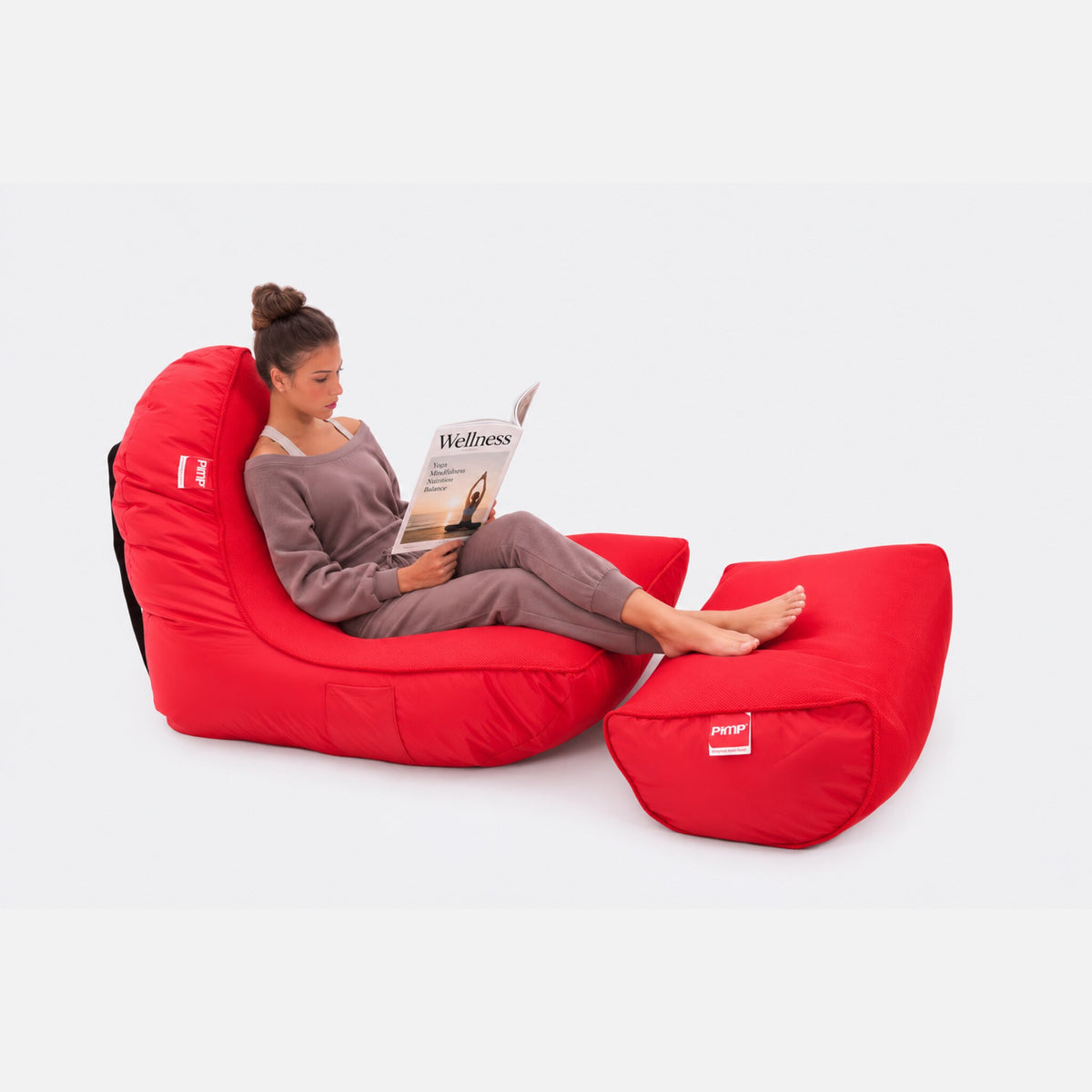 Woman reading with her feet up on the Street Cred Red sofa and ottoman